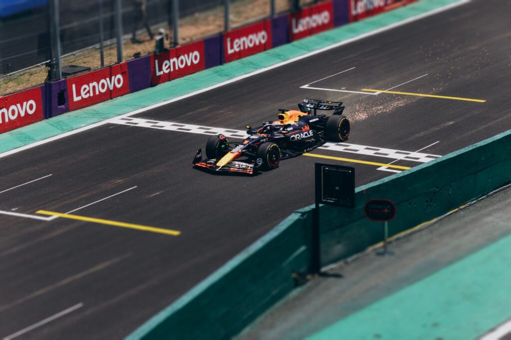 Formula 1 car speeding across the finish line on a racetrack, emitting sparks.