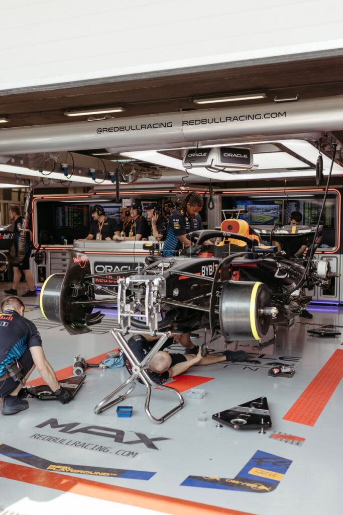 Pit crew actively working on a Formula 1 car in the garage, showing teamwork and precision.