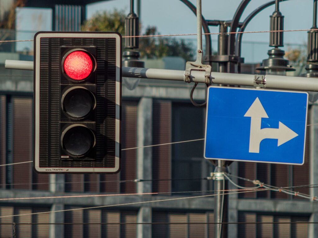 Red traffic light and directional road sign in Wrocław, Poland.