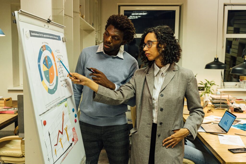 Colleagues engaged in a data-driven meeting, analyzing charts and graphs on a flipchart.