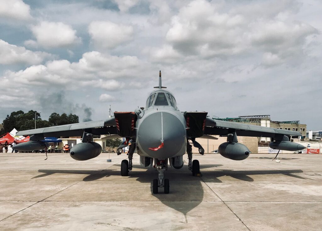 A parked military aircraft with a cloudy sky backdrop, showcasing aviation technology.