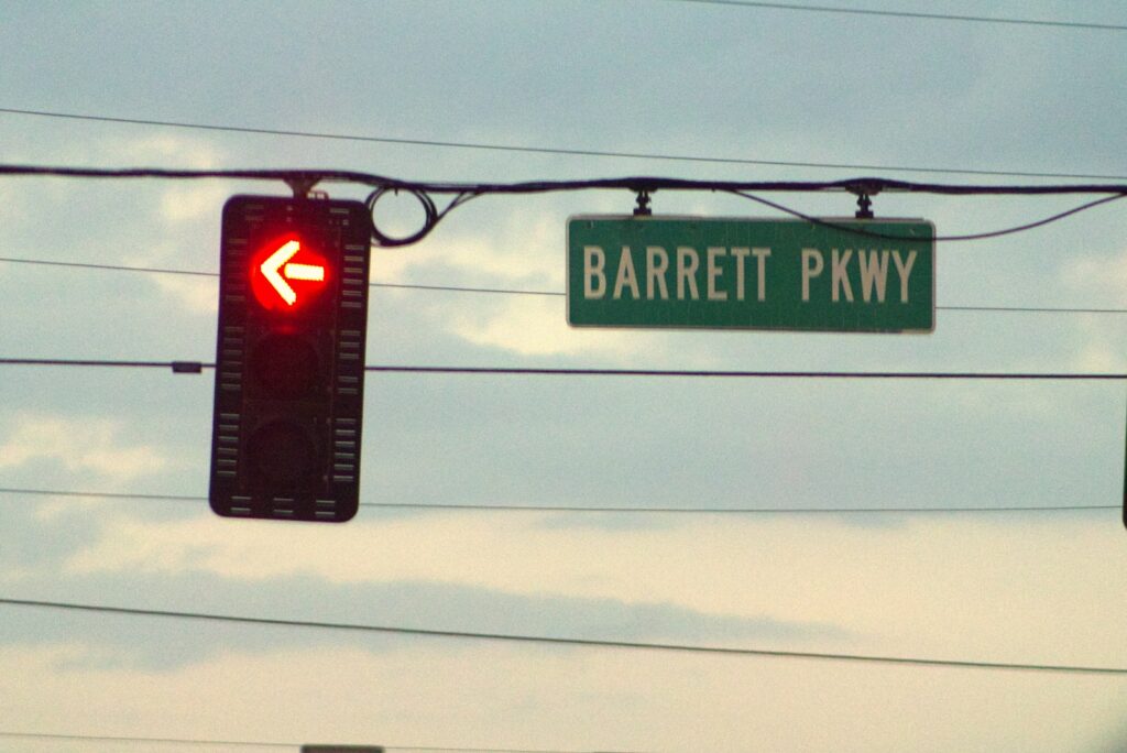 A traffic light with a street sign hanging from it's side