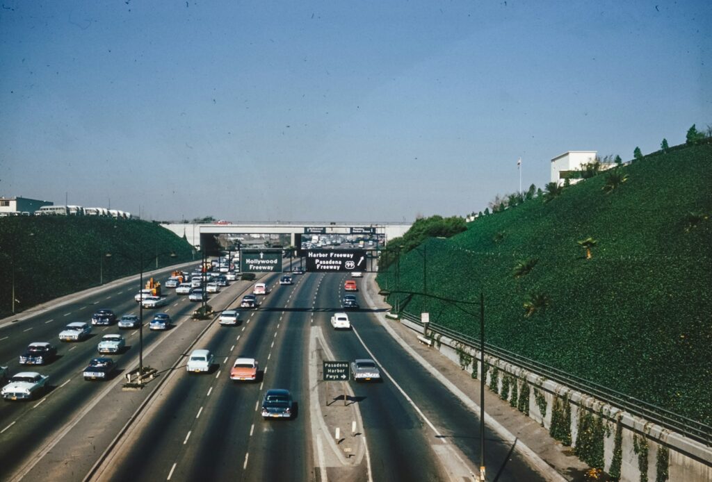 a highway filled with lots of traffic next to a lush green hillside