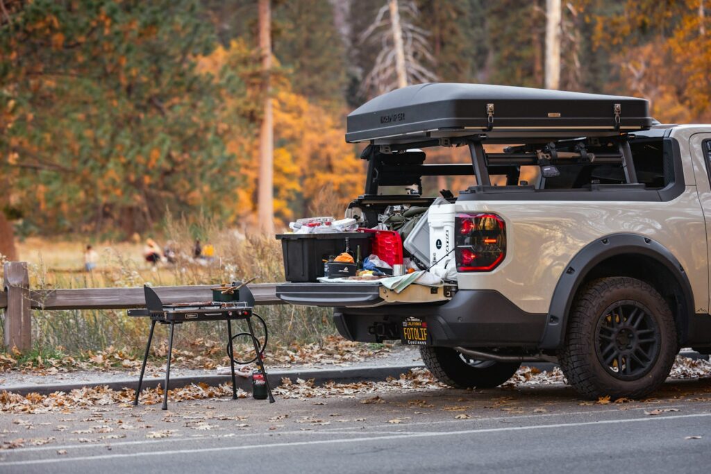 Truck bed camping setup with open tailgate and table.