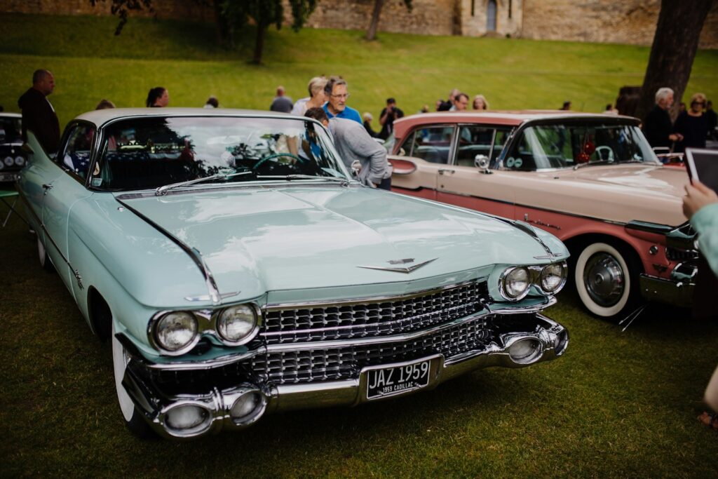 people standing beside red and white vintage car during daytime