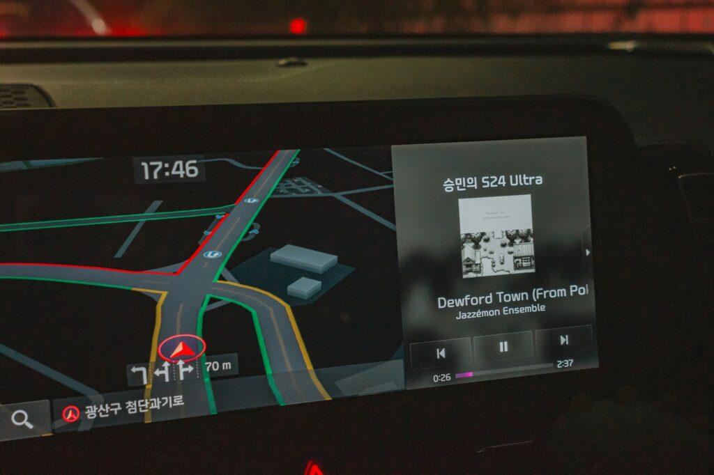 Car navigation screen showing map and music player