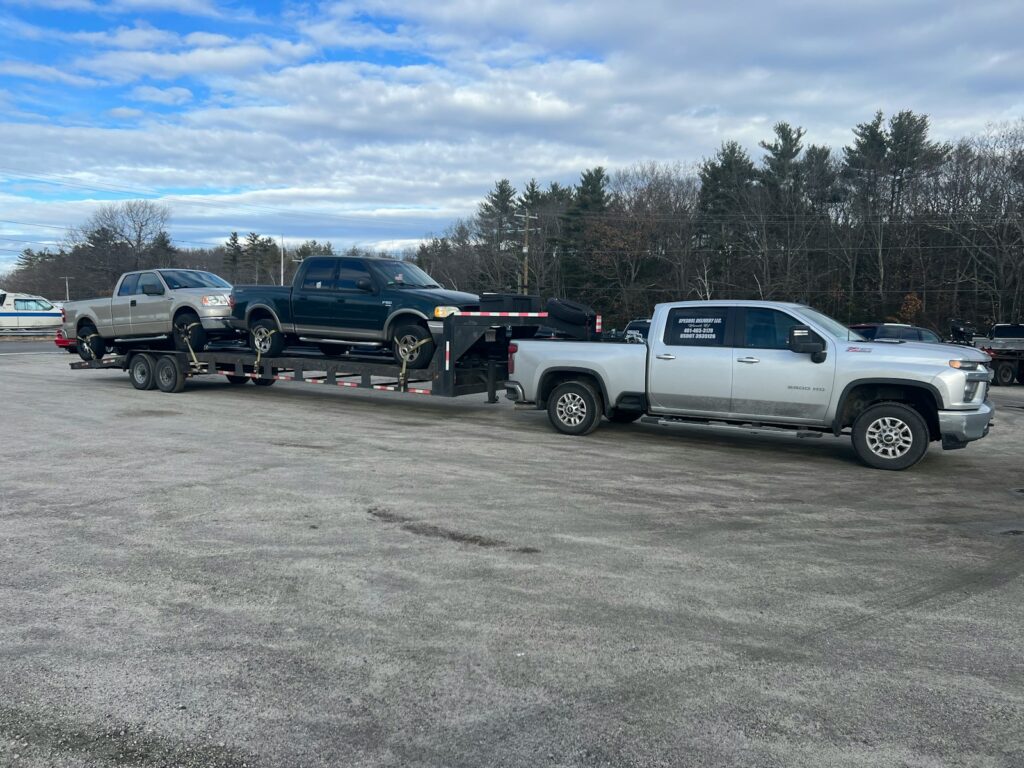 a tow truck towing a silver truck in a parking lot