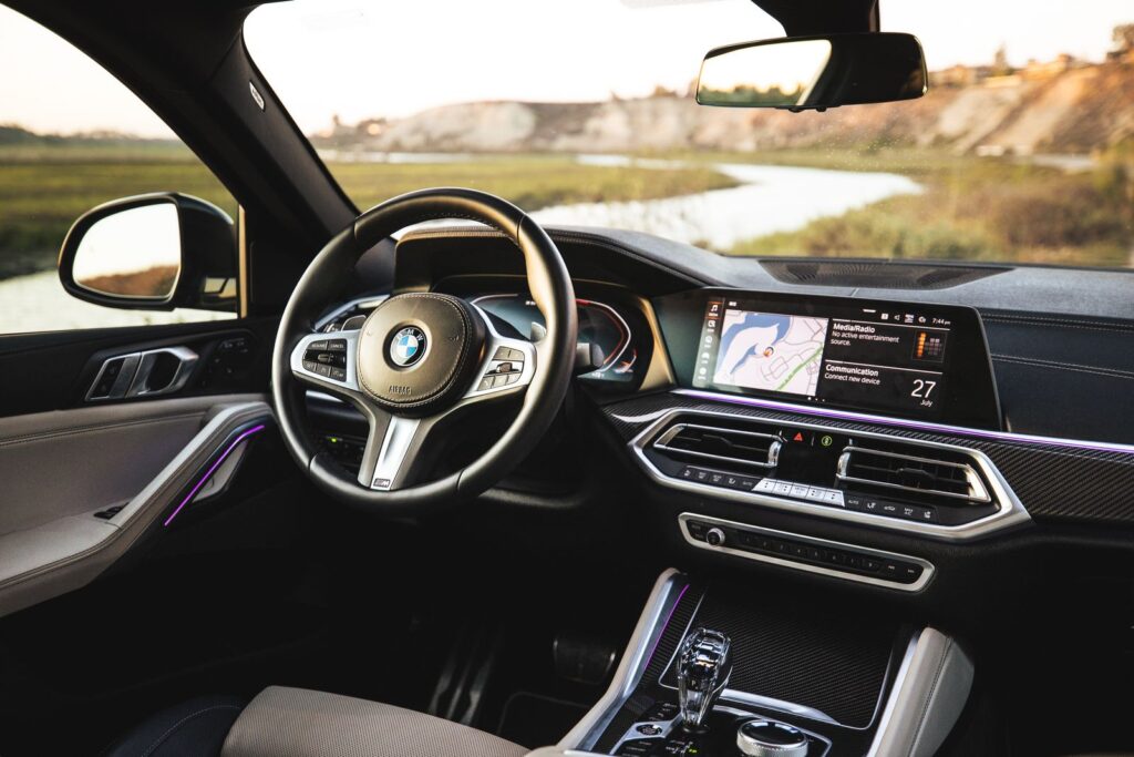 Explore the elegant BMW car interior with a modern navigation system by the scenic seashore.