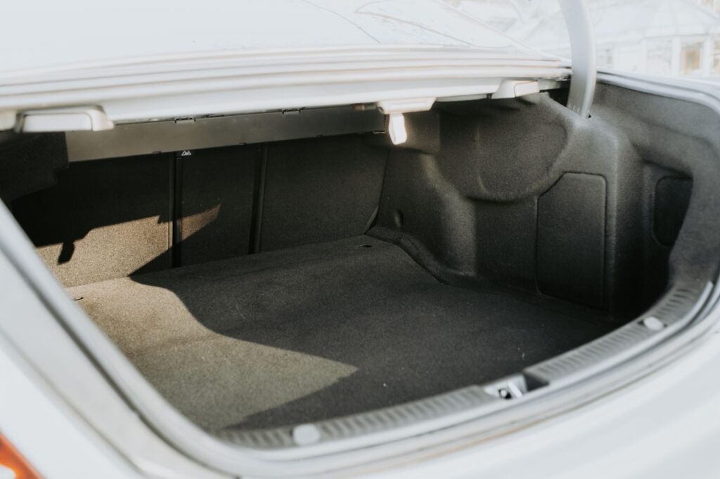 An empty car trunk highlighted by bright sunlight, showing ample space.