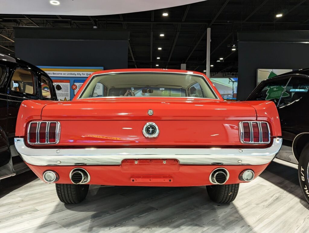 Rear view of a classic red Ford Mustang indoors, showcasing vintage car design.