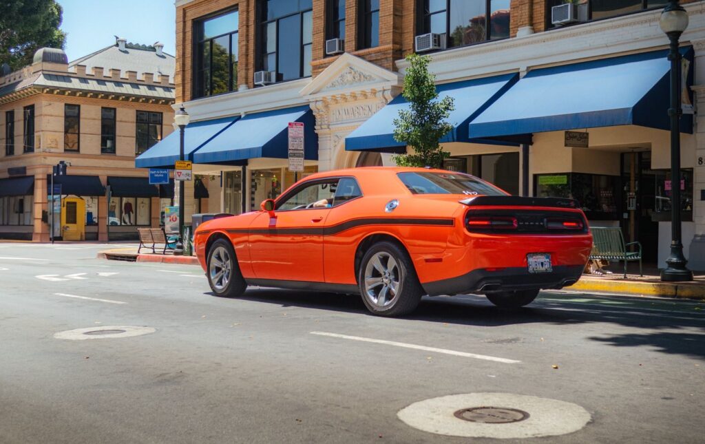 Vibrant orange Dodge Challenger parked on a sunny street in San Luis Obispo.