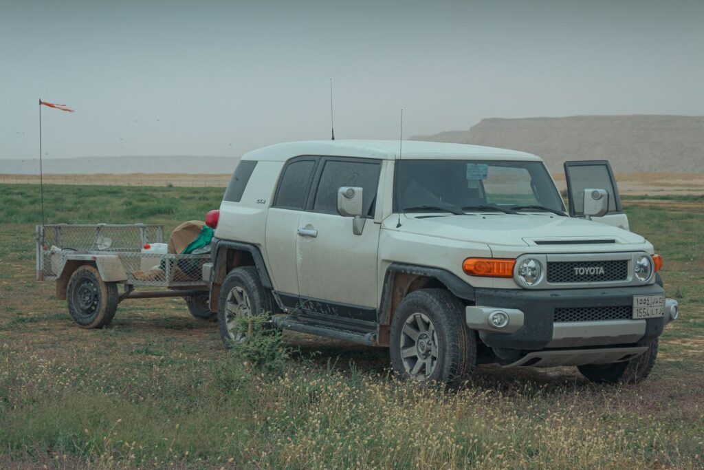 A rugged SUV with a trailer in the desert near Riyadh, perfect for off-road adventures.
