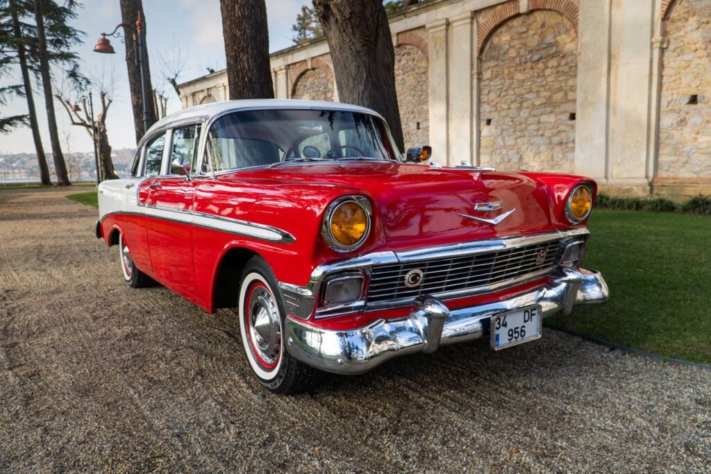 A beautifully restored classic red vintage car parked in an elegant outdoor setting, exuding timeless charm.