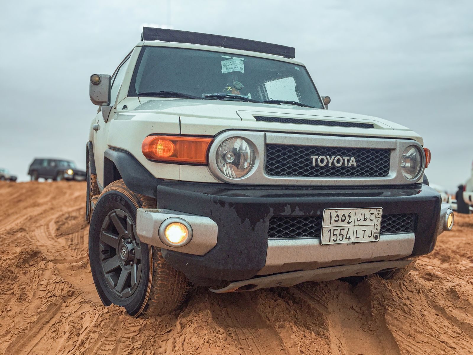 White Toyota FJ Cruiser navigating sandy terrain in Riyadh desert. Off-road adventure vibe.