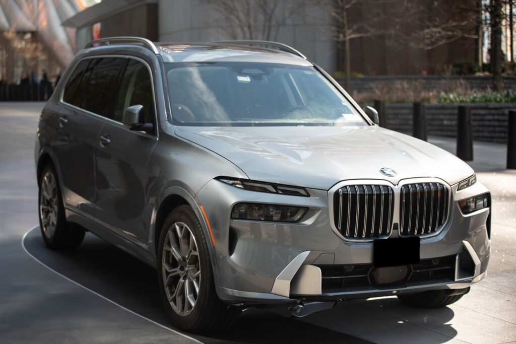 A silver luxury SUV parked outdoors in a modern urban area of New York City.