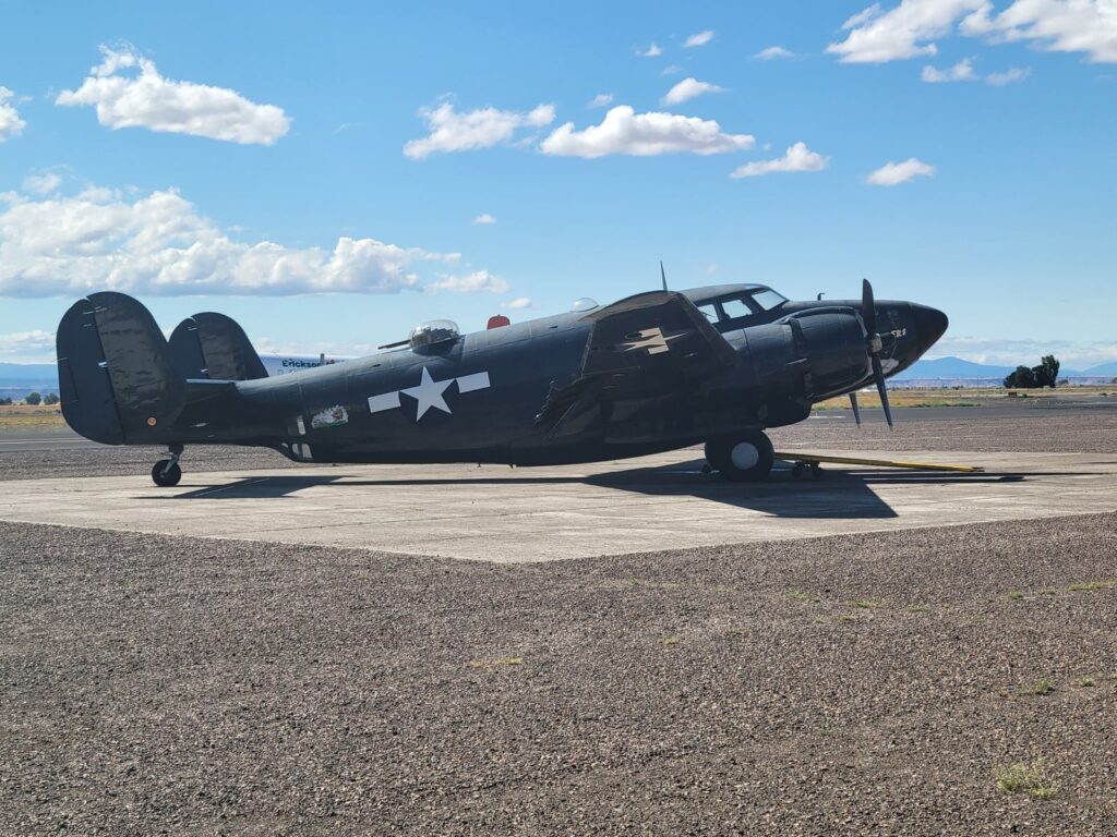 Vintage World War II military aircraft resting on a sunny airfield with clear skies in the background.