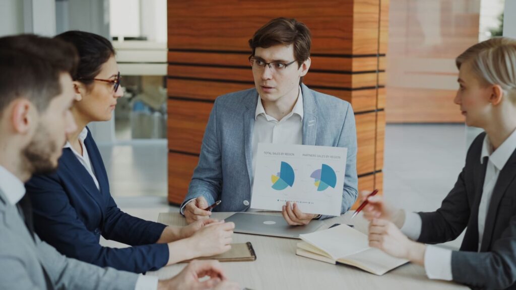 A team engaged in a business meeting discussing charts and strategies in an office.