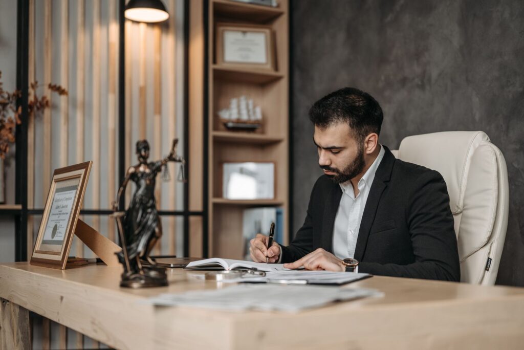 A focused lawyer in an office setting writing and reviewing legal documents, symbolizing expertise and professionalism.