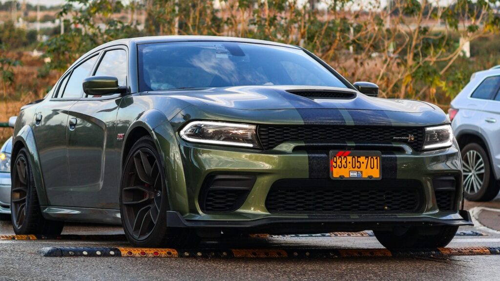 A green dodge charger sits parked on the street.