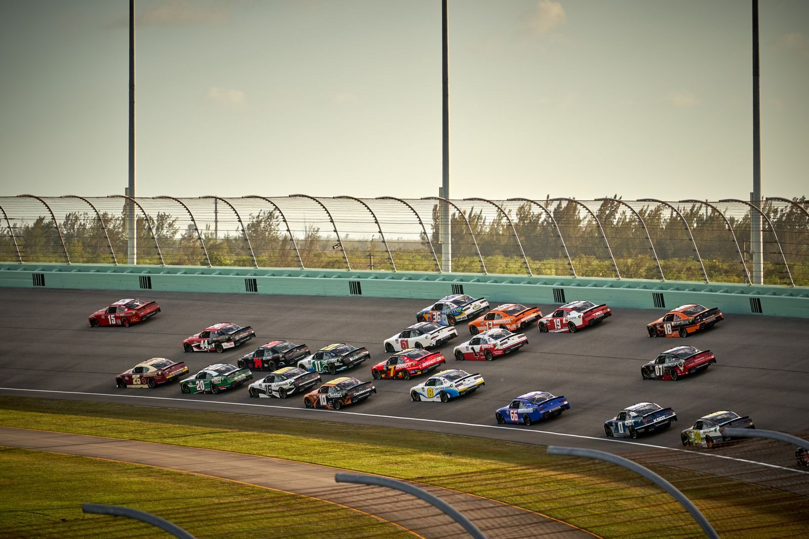 High-speed NASCAR race featuring multiple cars on a sunny day in Miami.