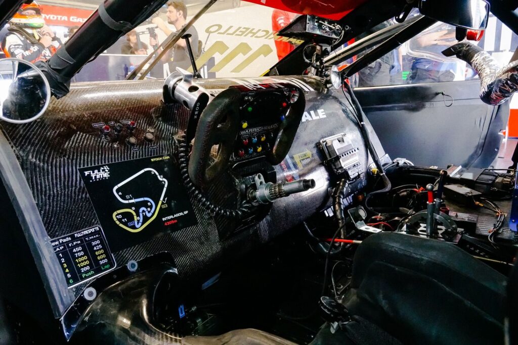 Detailed view of a racing car's cockpit highlighting the carbon fiber dashboard and steering wheel.