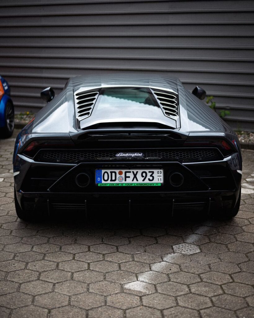 Stunning rear view of a sleek black Lamborghini Huracan parked outdoors, showcasing its sleek design and luxury appeal.