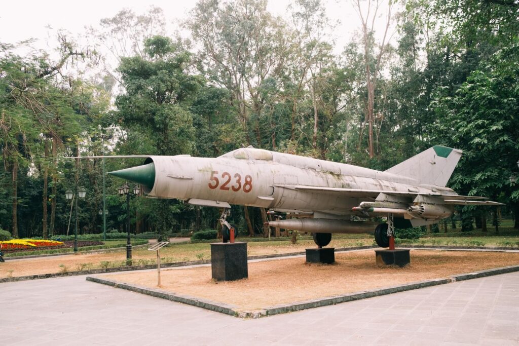 Old military jet fighter on display in a lush green park.