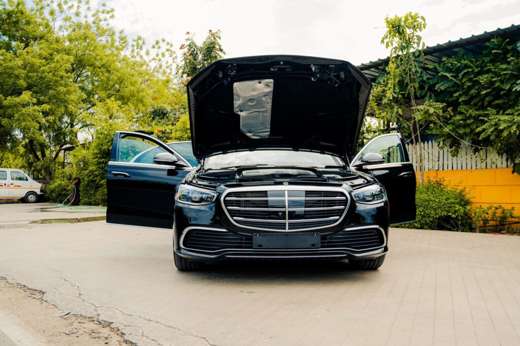 Front view of a luxury black Mercedes-Benz with hood and doors open, outdoors.