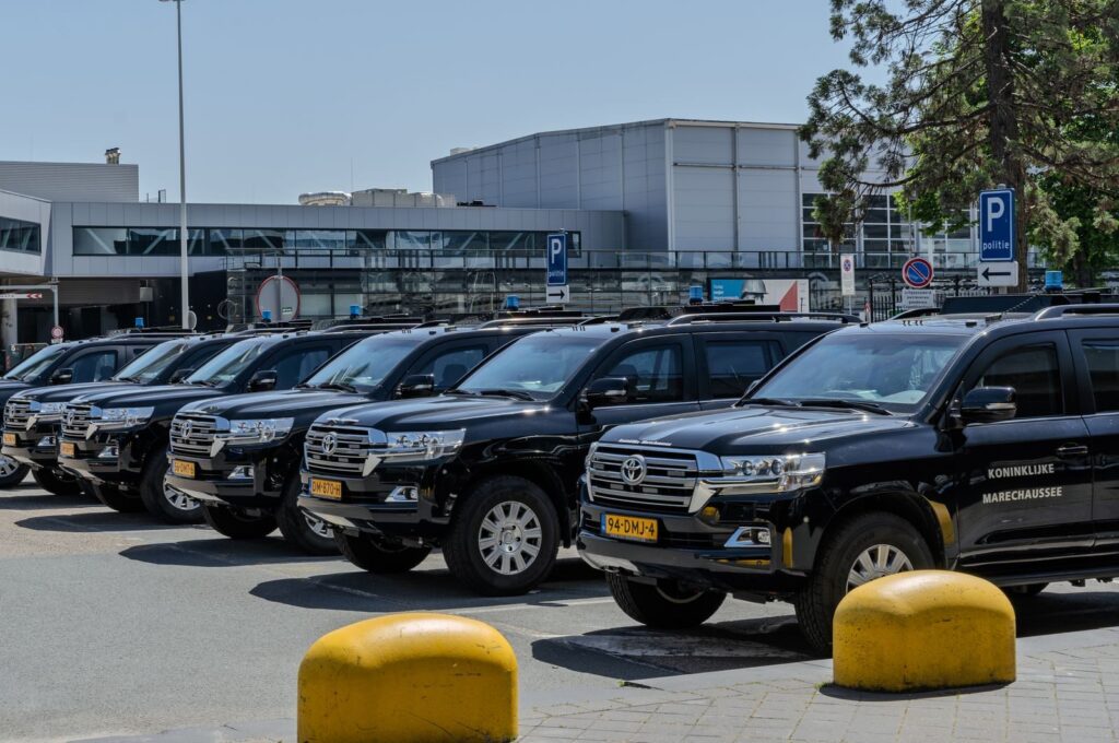 Black SUV police vehicles lined up at an airport parking area under clear skies.