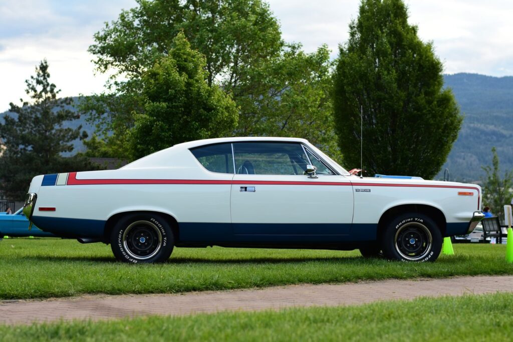 Side view of a classic vintage car parked outdoors on a lush green lawn.