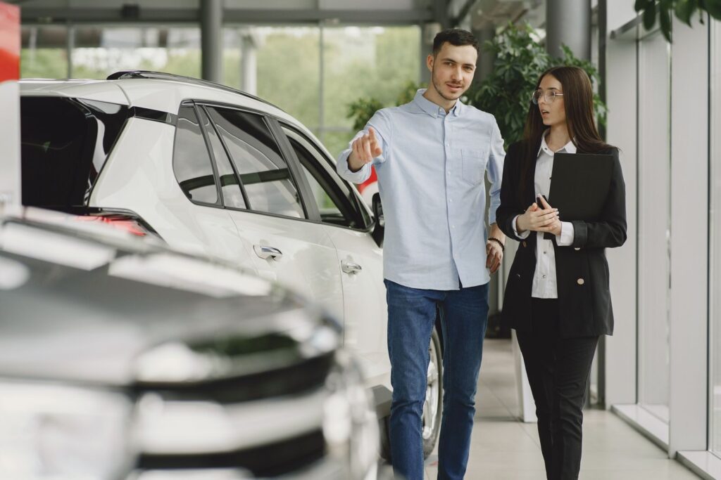 Customer and salesperson discussing a vehicle inside a modern car dealership showroom.