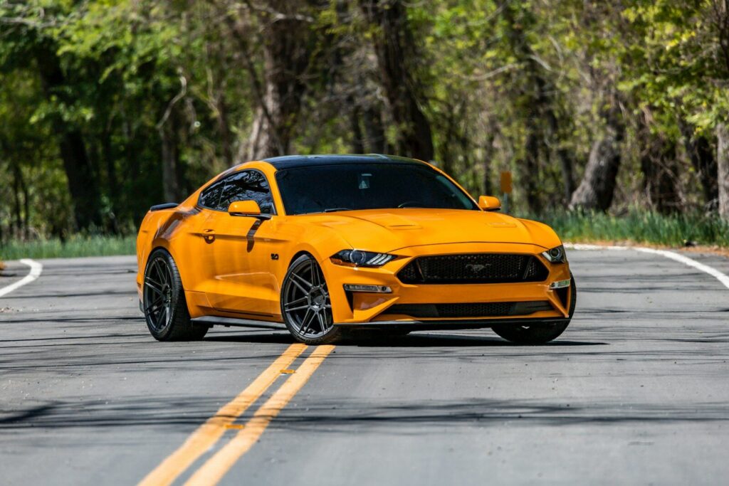 a yellow ford mustang driving down the road