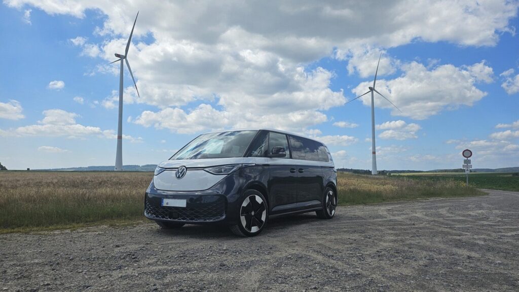 A dark blue and white van parked near wind turbines