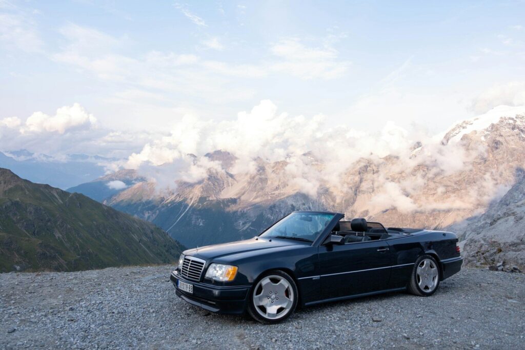 Dark convertible car parked on a rocky mountain overlook