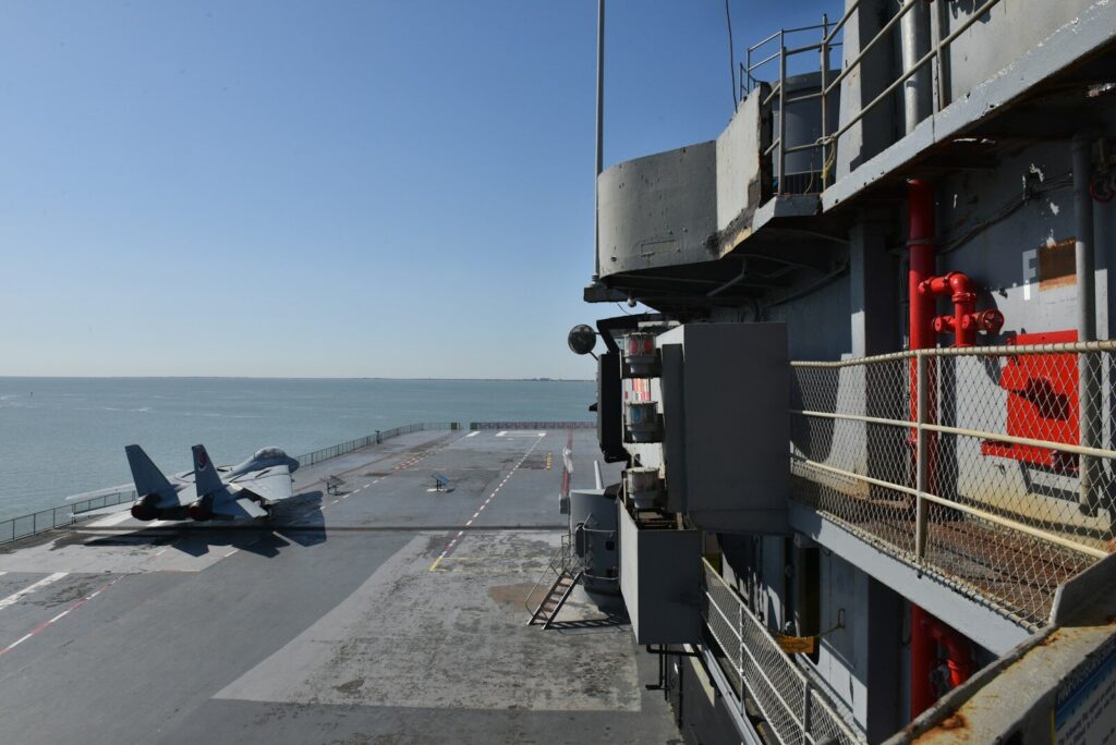 Two fighter jets on an aircraft carrier deck at sea.