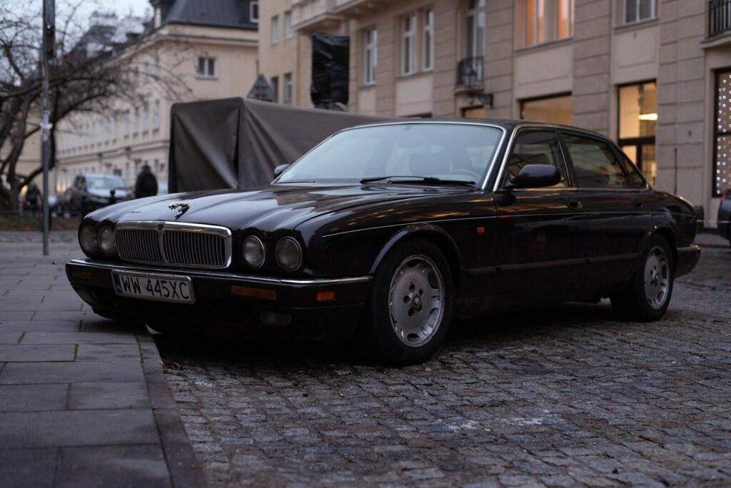 a black car parked on a cobblestone street
