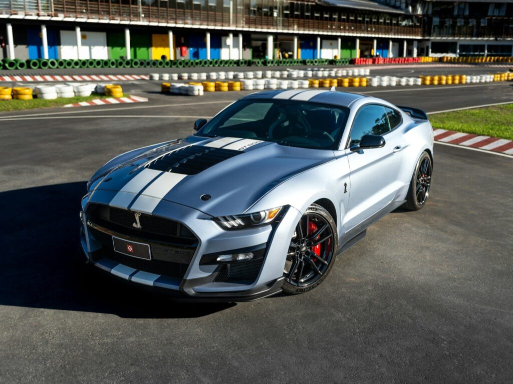 A silver shelby mustang is shown on a racetrack