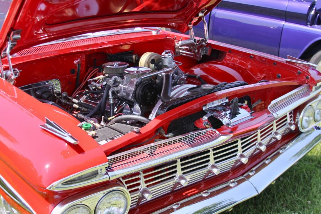 A detailed shot of a vintage red car with an open hood, showcasing its engine in Missouri.
