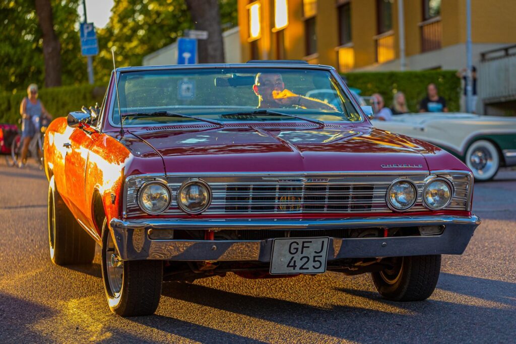 A vintage red convertible car shines in the sun, capturing nostalgia and style.