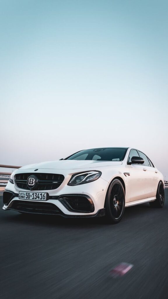 Dynamic capture of a luxury white sedan speeding on a clear highway. Ideal for automotive themes.