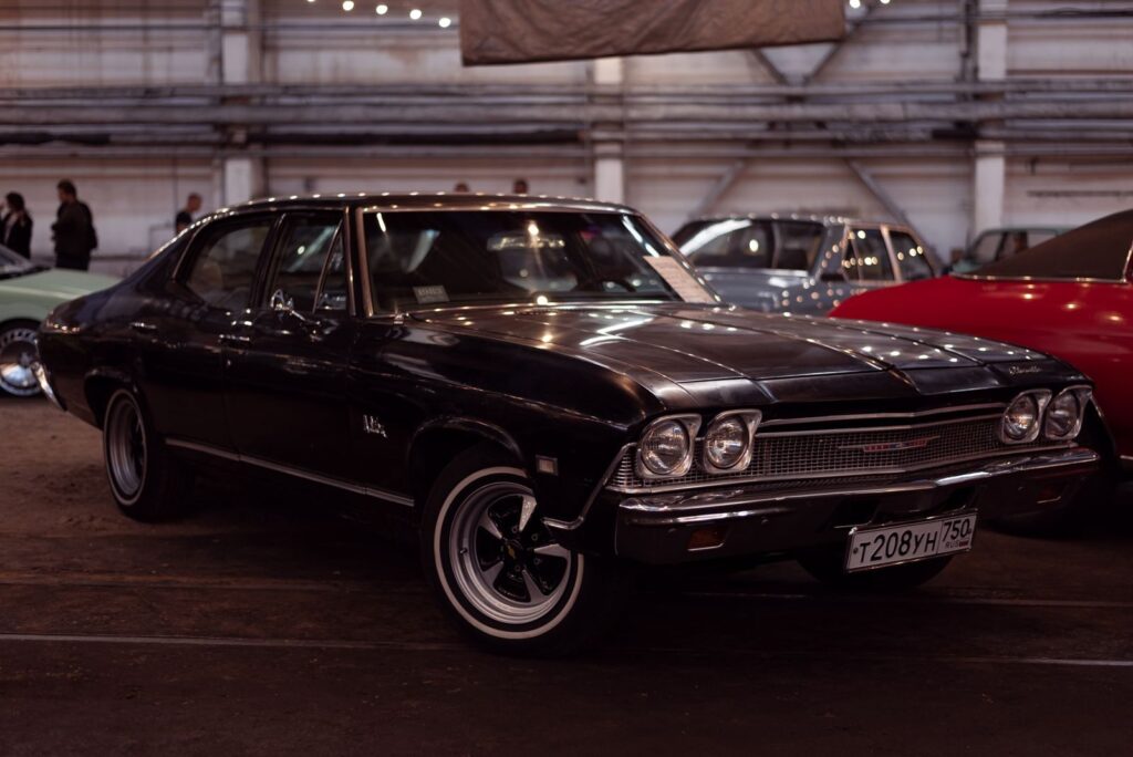 Classic black vintage car showcased at an indoor auto exhibition, highlighting retro design.