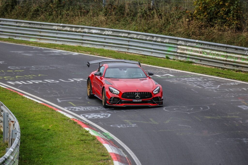 A sleek red sports car takes a sharp turn on a famous racing circuit, showcasing speed and agility.
