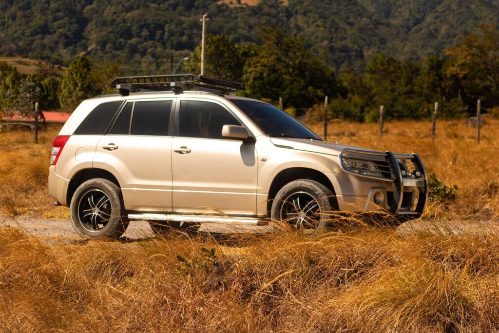 A Suzuki Grand Vitara parked in a rural landscape scene, offering an adventurous vibe.
