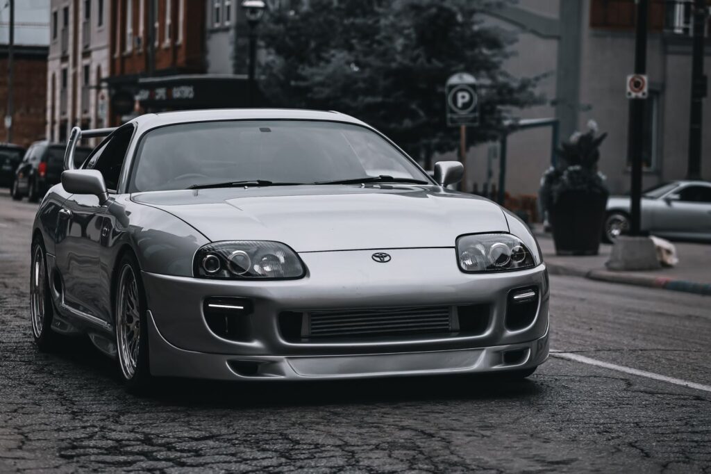 Sleek silver Toyota Supra parked on a gritty urban street, showcasing modern automotive design.