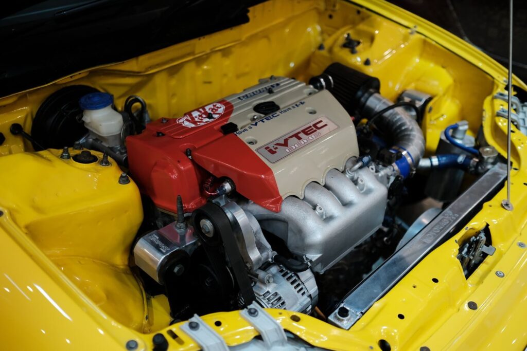 Close-up of a high-performance VTEC engine in a yellow Honda, showcasing automotive engineering.