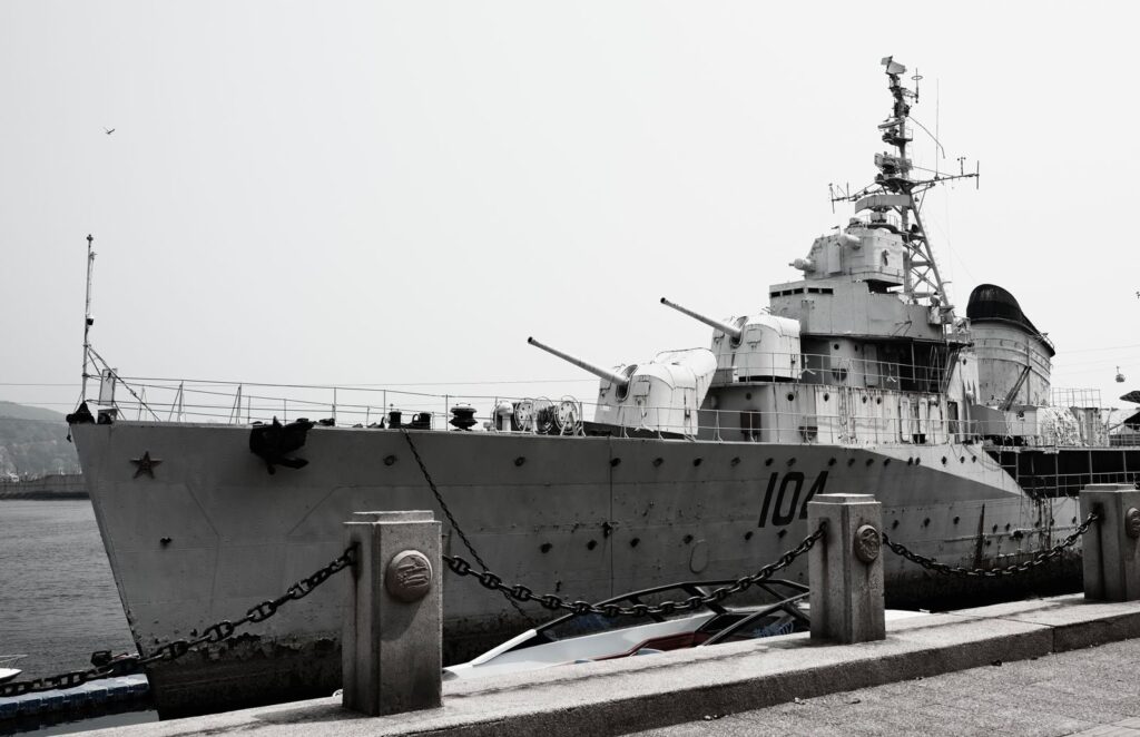 A large naval destroyer ship docked at a harbor under a gray sky.