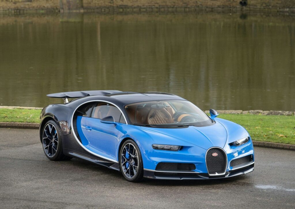 a blue bugatti is parked in front of a body of water