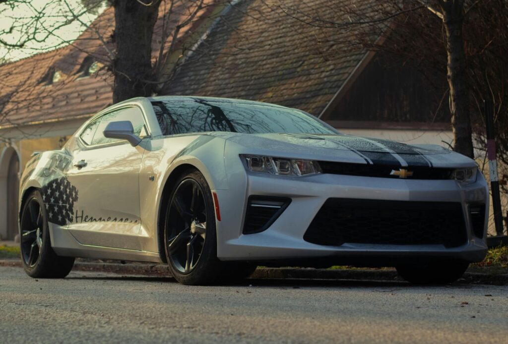A white Chevrolet Camaro parked on a city street under trees, capturing the essence of urban auto style.