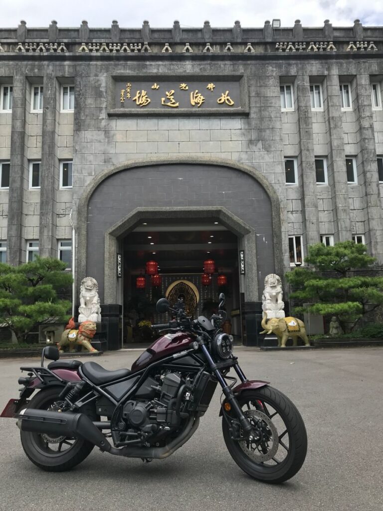 A black motorcycle parked outside a traditional Taiwanese temple with ornate decorations.