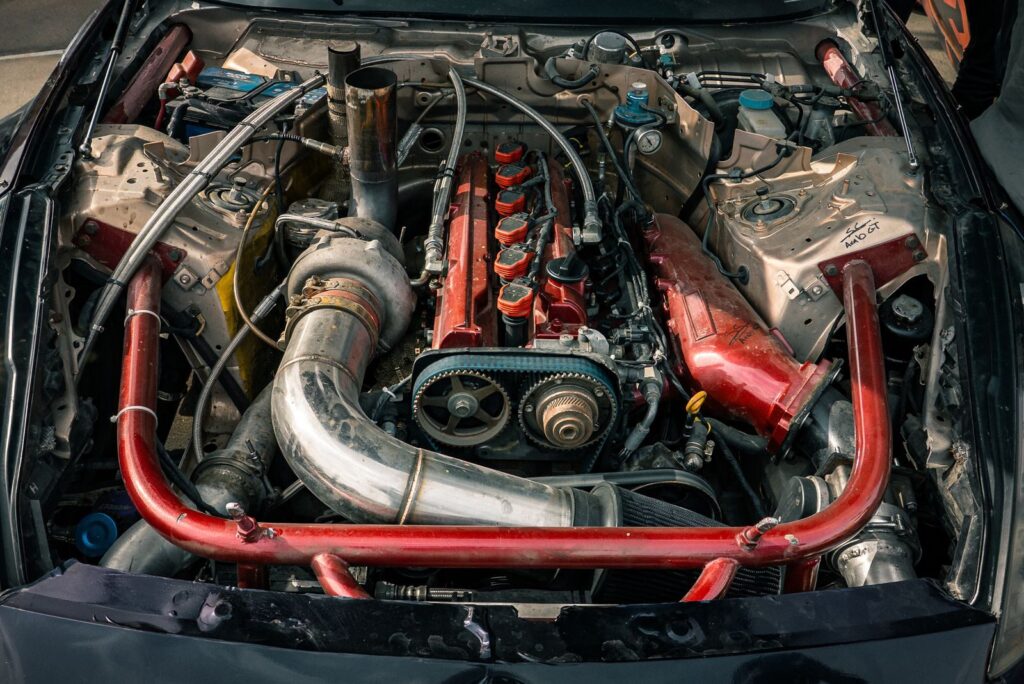 Detailed view of a modified car engine with red accents, showcasing its components.